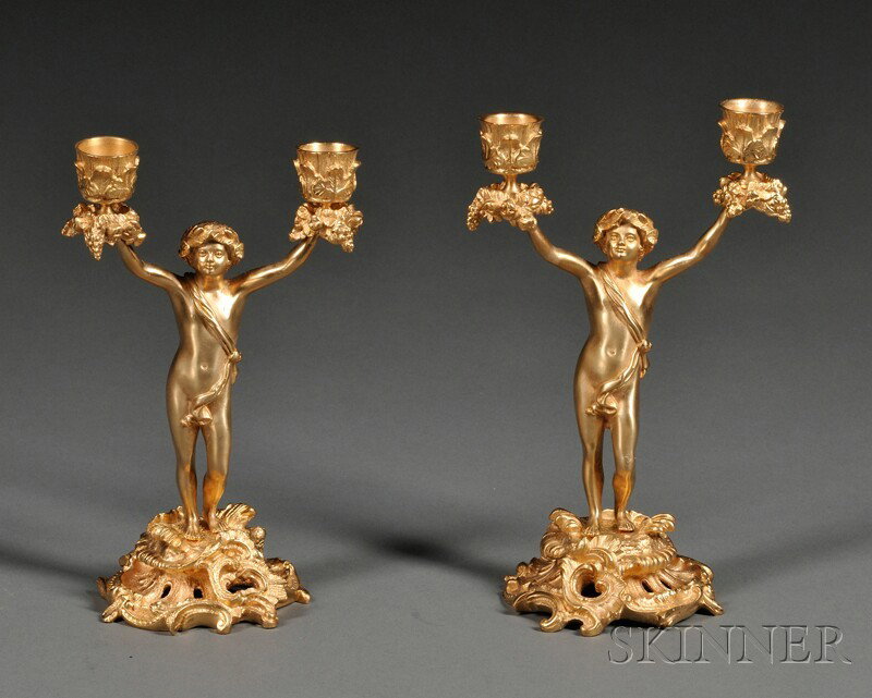 Pair of Dore Bronze Figural Candelabra, Continent: Pair of Dore Bronze Figural Candelabra, Continental, 20th century, each modeled as a scantily clad man supporting candle nozzles adorned with fruits and flowers at either hand and standing on pierced 