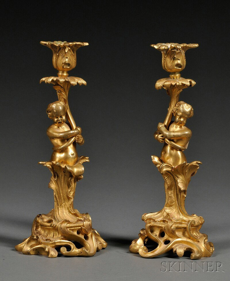 Pair of Dore Bronze Figural Candlesticks, France,: Pair of Dore Bronze Figural Candlesticks, France, 19th century, each with foliate nozzle supported by as cherub set among leaves to a scrolled and pierced rococo-style base, ht. 9 7/8 in.