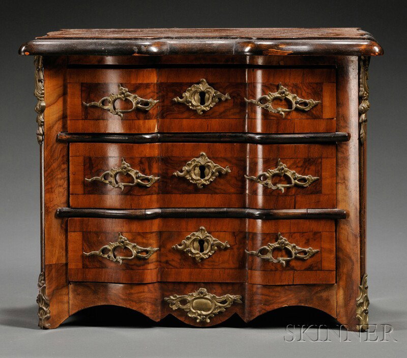 Miniature Chest of Three Drawers, Continental, ea: Miniature Chest of Three Drawers, Continental, early 20th century, veneered and with scrolled foliate gilt-metal handles, escutcheons and corner mounts, each drawer with a fitted interior, ht. 11, lg.