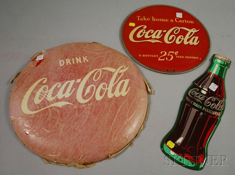 Three Coca-Cola Painted Tin Signs, c. 1940-52, a d: Three Coca-Cola Painted Tin Signs, c. 1940-52, a display, a bottle-form, and a button, (unused), dia. 13, lg. 16 3/4, and dia. 16 in., respectively.