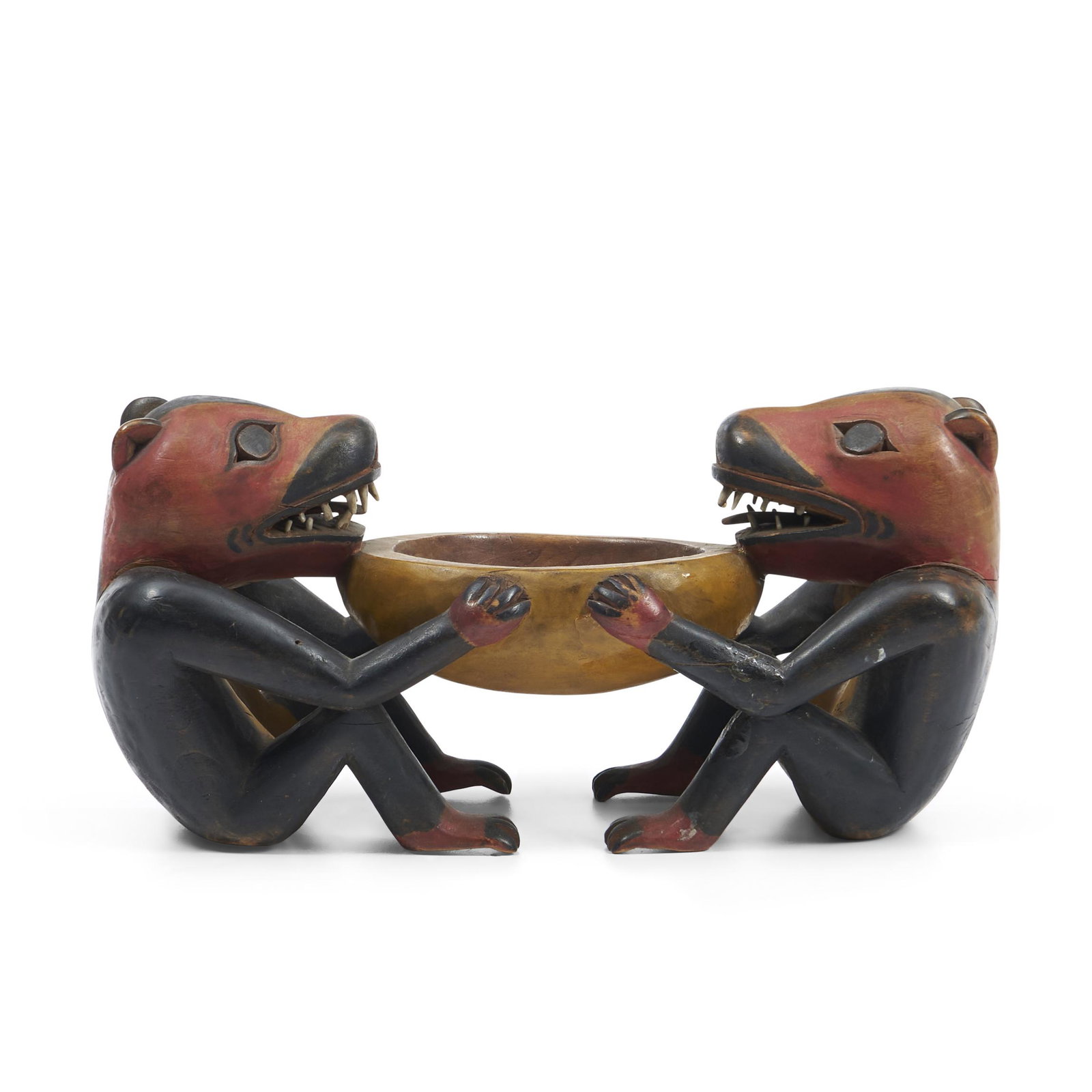 A Northwest Coast polychrome wood bowl ht. 4 1/2 wd. 9 in.: A Northwest Coast polychrome wood bowl Two identical seated animals holding a small bowl, teeth made from bone, (age cracks in the wood and restoration to breaks in two arms). ht. 4 1/2 wd. 9 in.