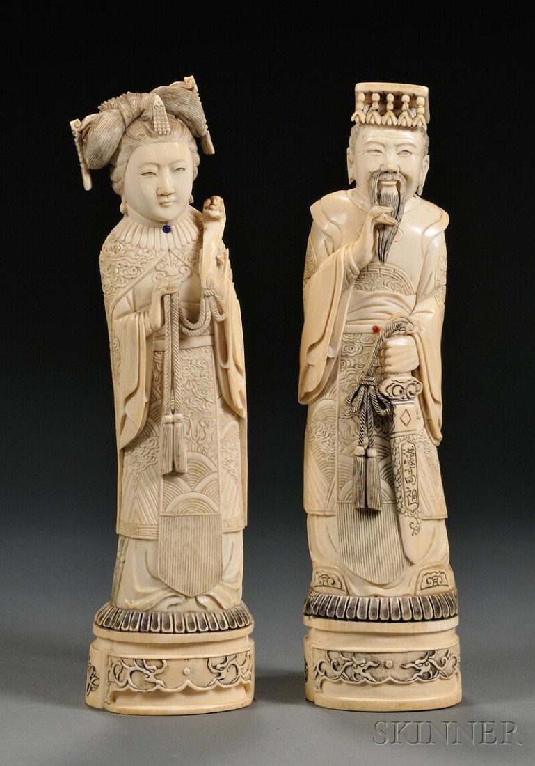 Pair of Ivory Carvings, China, late 19th century, : Pair of Ivory Carvings, China, late 19th century, depicting standing figures of an emperor and empress, their robes elaborately carved in relief with dragons and phoenixes, Qianlong mark to the base, 