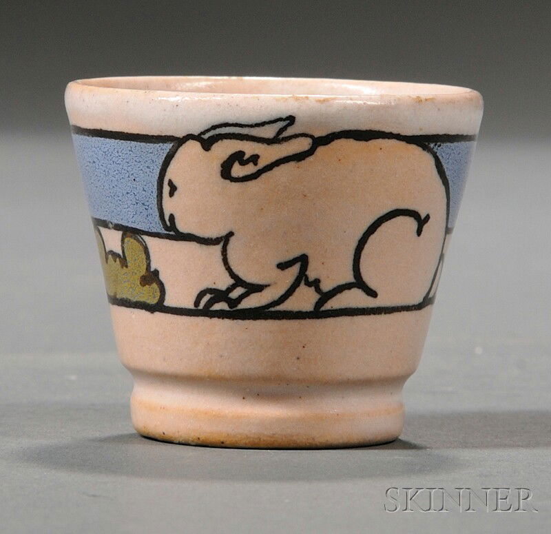 Saturday Evening Girls Egg Cup Glazed earthenware Boston, Massachusetts Small glazed cup with rabbit: Saturday Evening Girls Egg Cup Glazed earthenware Boston, Massachusetts Small glazed cup with rabbit decoration and a blue band on white ground, with S.E.G. in black ink with artist's signature and da