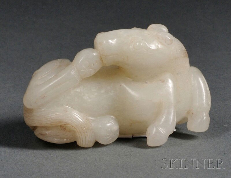 Jade Carving, China, 19th century, depicting a rec: Jade Carving, China, 19th century, depicting a recumbent horse, with its head turned backwards touching one hoof, the stone of semi-translucent celadon-white color with dark streaking, ht. 1 1/4, lg.