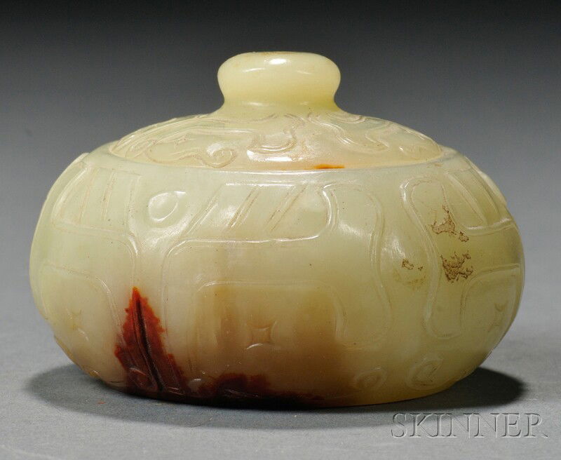 Jade Box, China, small round box and cover, carve: Jade Box, China, small round box and cover, carved with taotie masks, stone of yellow-celadon color with deep russet marking to base, dia. 1 7/8 in.