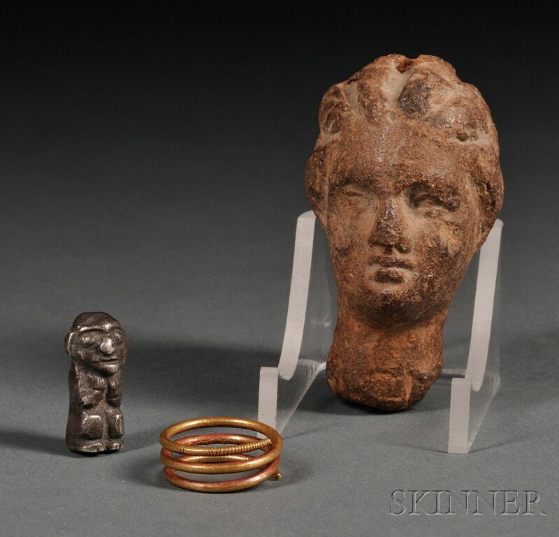 Three Ancient Articles, an Egyptian coiled gold ri: Three Ancient Articles, an Egyptian coiled gold ring, size 6 1/2-7; a Hellenic carved stone head, ht. 2 3/4; and a South American pre-Columbian silver totem figure, ht. 1 in. Provenance: Descended in 