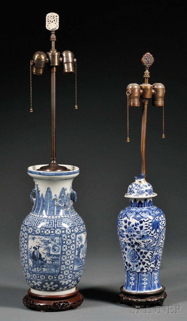 Two Chinese Blue and White Porcelain Lamp Bases, o: Two Chinese Blue and White Porcelain Lamp Bases, one with foo dog-topped lid and body decorated with dragons, the other double-handled with scenic panels on ornamental body, on carved wood stands, ht.