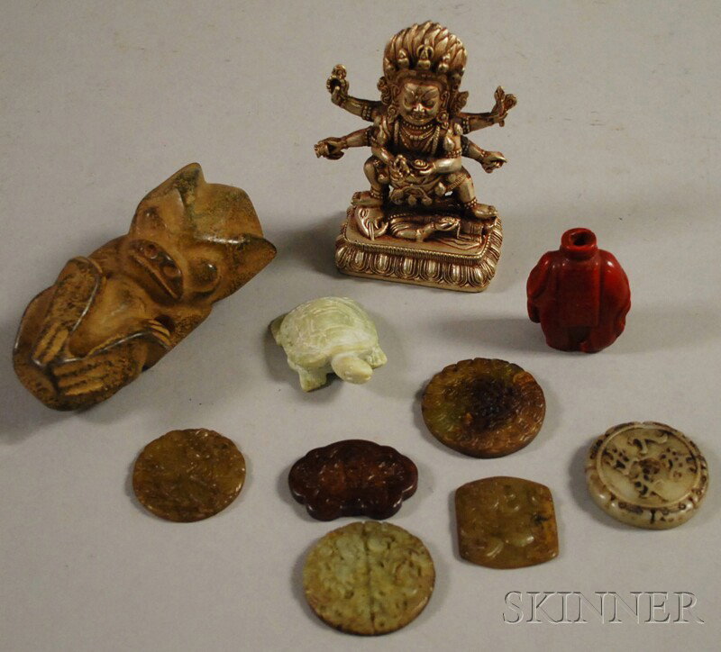 Ten Assorted Small Asian Items, a silvered metal: Ten Assorted Small Asian Items, a silvered metal deity figure, a primitive carved stone figure, six carved jade and hardstone pendants, a carved soapstone turtle figure, and a cinnabar elephant snuff