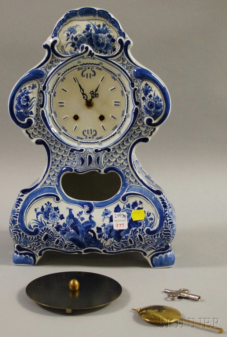 Delft Blue and White Porcelain Mantel Clock, with: Delft Blue and White Porcelain Mantel Clock, with German brass spring-wound movement, overall floral decoration with a scene of birds and flowers to the base, raised on four bracket legs, marked insid