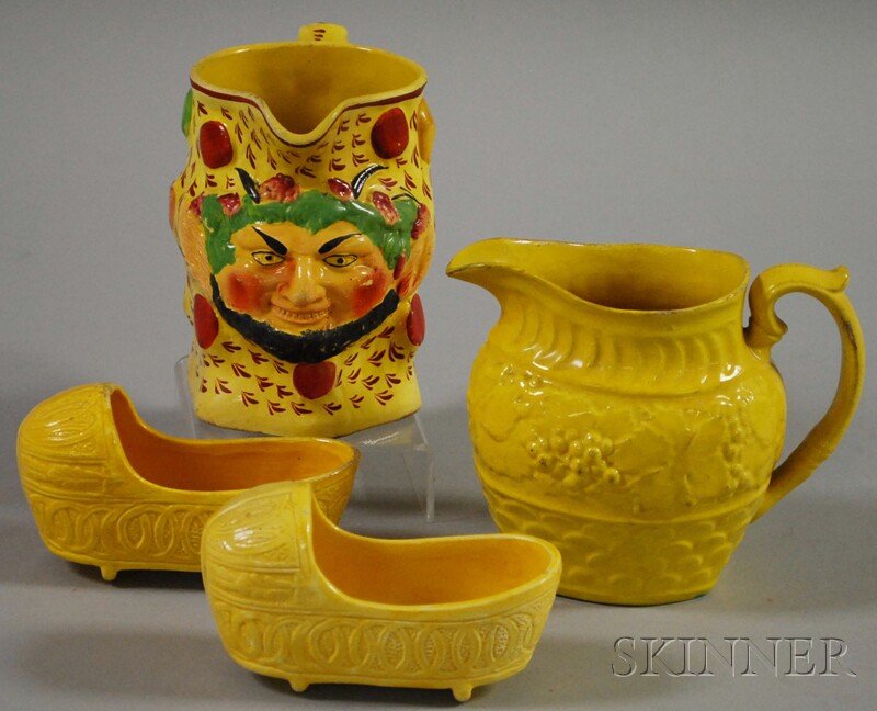 Four Yellow-glazed Staffordshire Pottery Items, a: Four Yellow-glazed Staffordshire Pottery Items, a pair of small cradles and two jugs, one with grotesque multicolored demon face to front, ht. to 5 1/8 in.