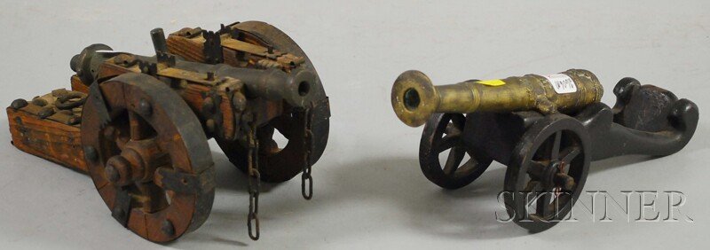 Two Bronze and Wood Signal Cannons, one has bronze: Two Bronze and Wood Signal Cannons, one has bronze gun with raised shield and crown motif, with sheet-iron-mounted wooden carriage, the other with cast belted bronze gun on a wooden carriage, ht. 4 7/