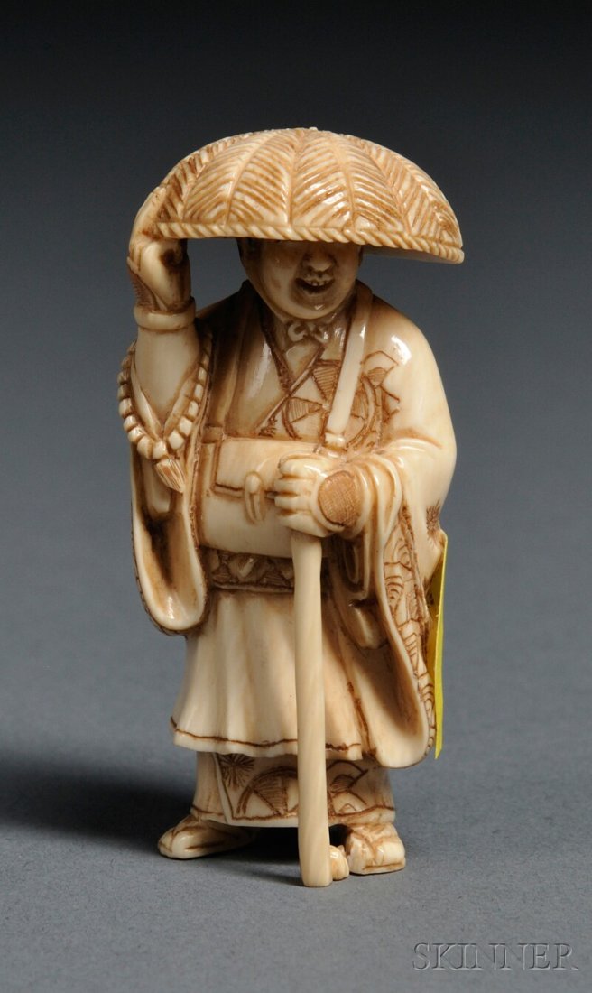 Ivory Netsuke, Japan, 19th century, in the form of: Ivory Netsuke, Japan, 19th century, in the form of a standing monk holding a staff and prayer beads, signed, ht. 2 in.