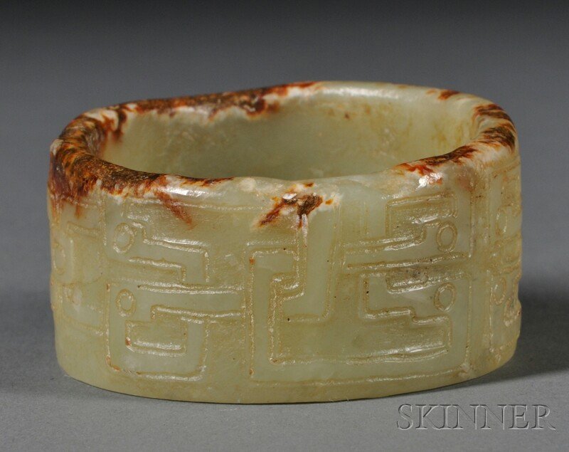 Jade Bangle, China, possibly Zhou Dynasty (1046-22: Jade Bangle, China, possibly Zhou Dynasty (1046-221 B.C.), circular form carved in shallow relief with archaic interlocking scrolls, stone of celadon color with russet inclusions, dia. 2 1/8 in.