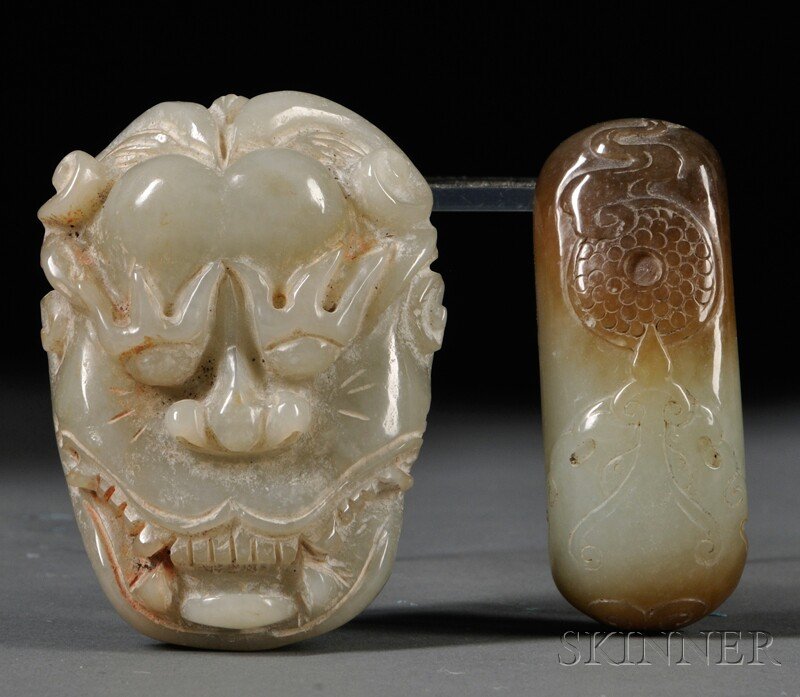 Two Jade Belt Buckles, China, 20th century, one de: Two Jade Belt Buckles, China, 20th century, one depicting a human face, stone of pale celadon color, lg. 2 1/2, one depicting a dragon's face and a coin, gray stone with dark markings, lg. 2 1/2 in.