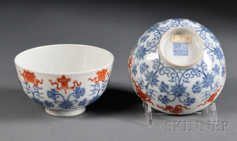 Pair of Porcelain Bowls, China, 19th/20th century,: Pair of Porcelain Bowls, China, 19th/20th century, each decorated with scrolling lotus flowers in blue, with the Eight Buddhist Emblems painted in iron-red along the mouth, the recessed base with six-