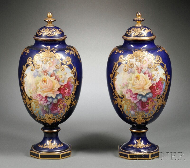 Pair of Franz Anton Earthenware Factory Hand-paint: Pair of Franz Anton Earthenware Factory Hand-painted Ceramic Covered Urns, Germany, late 19th/early 20th century, each with a gilt finial cover and central painted floral cartouche signed "B. Gussger"