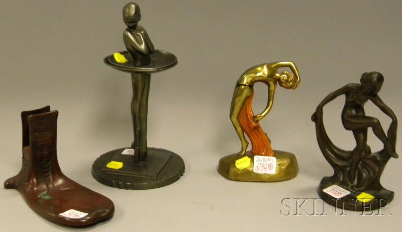 Four Art Nouveau and Art Deco Metal Table Items, a: Four Art Nouveau and Art Deco Metal Table Items, an Art Nouveau patinated metal match stand/tray, an Art Deco Frankart silver gray figural two-part stand, cast iron figural bookend, and gilt and paint