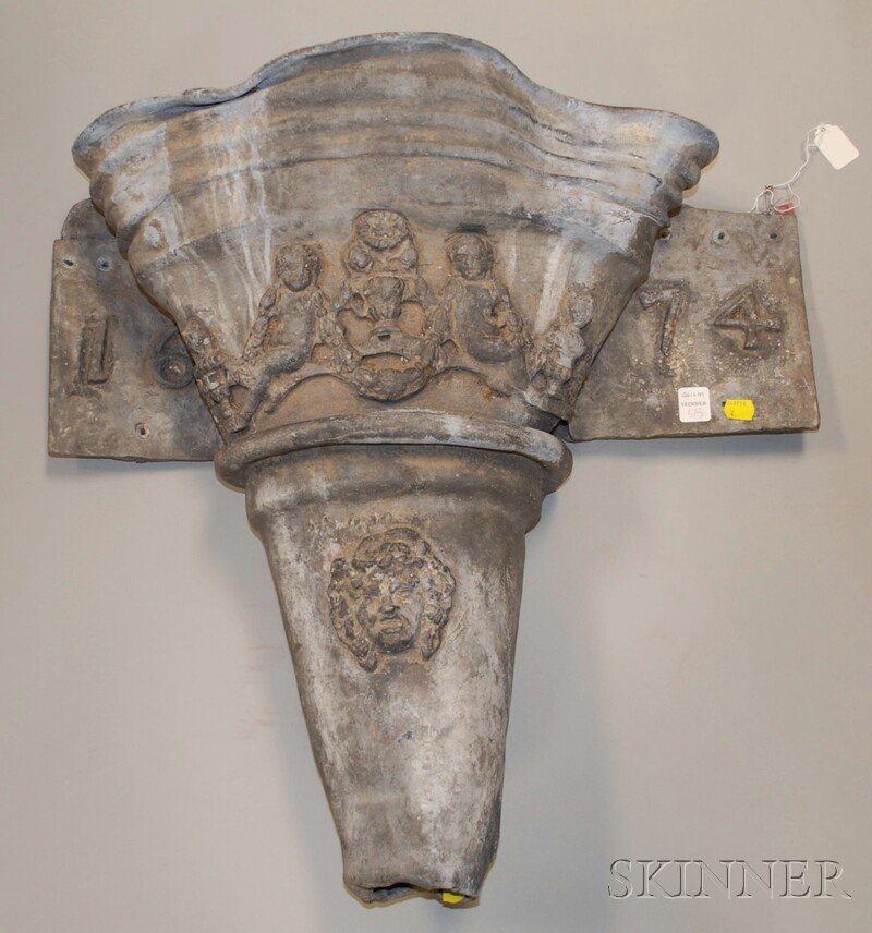 Architectural Lead Wall Downspout, horizontal back: Architectural Lead Wall Downspout, horizontal backing dated 1674, with wide shaped mouth decorated with a band of two putti separated by urns and a lower grotesque mask, ht. 21 1/2, wd. 23, dp. 7 3/4 