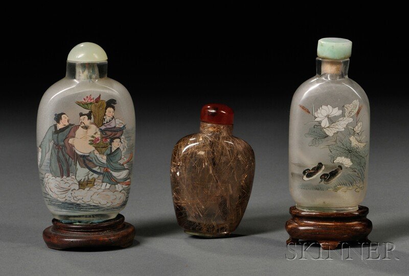 Three Snuff Bottles, China, one rutilated quartz o: Three Snuff Bottles, China, one rutilated quartz of flattened hu shape, the gray glass body infused with a network of lines of various length, carnelian stopper, ht. 2 1/8, the other two interior-pain