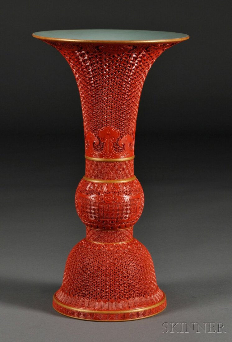Cinnabar Porcelain Gu Vase, China, with wide flari: Cinnabar Porcelain Gu Vase, China, with wide flaring rim and spreading foot, decorated with ruyi motifs and geometric ground, six-character Qianlong mark on the bulging mid-section, turquois