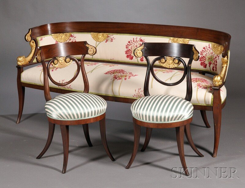 Empire-style Mahogany Veneer and Parcel-gilt Seati: Empire-style Mahogany Veneer and Parcel-gilt Seating Suite, early 20th century, a settee and two side chairs, the settee with D-shaped seat back with mask-adorned fan-form mounts, and on dolphin-form 
