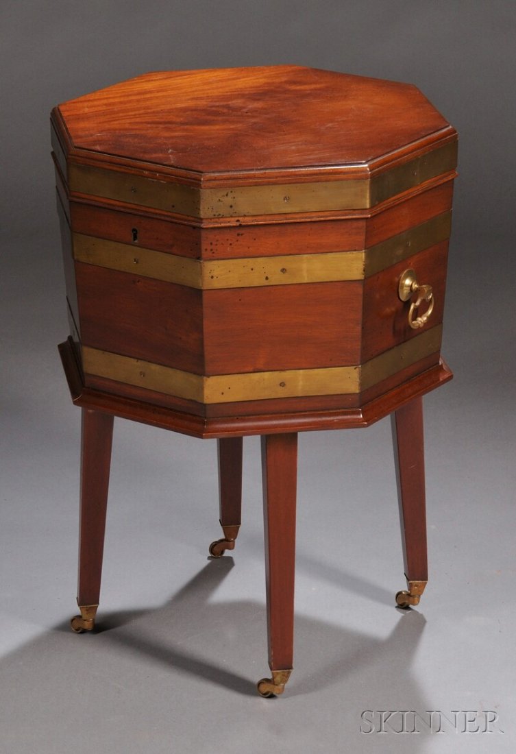 George III-style Mahogany and Brass-bound Cellaret: George III-style Mahogany and Brass-bound Cellarette, England, late 19th century, octagonal form with lead insert to the interior, mounted with three brass bands and a pair of brass bail handles, rais