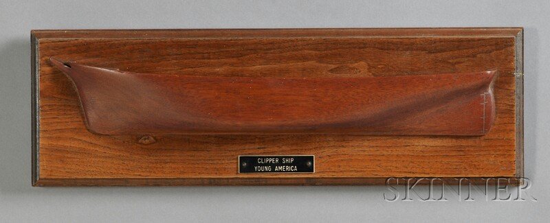 Mounted Mahogany Half-hull Model of the Clipper Sh: Mounted Mahogany Half-hull Model of the Clipper Ship YOUNG AMERICA, the carved vessel identified in a label on a molded walnut plaque, 5 3/4 x 18 in. overall.