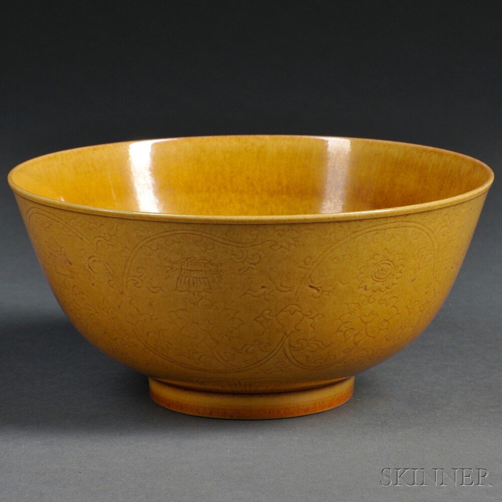 Yellow-glazed Bowl, China, 20th century, decorated: Yellow-glazed Bowl, China, 20th century, decorated with the eight Buddhist emblems and scrolling lotus flowers, covered with a rich yellow glaze with slight crackling, six-character Qianlong mark on b