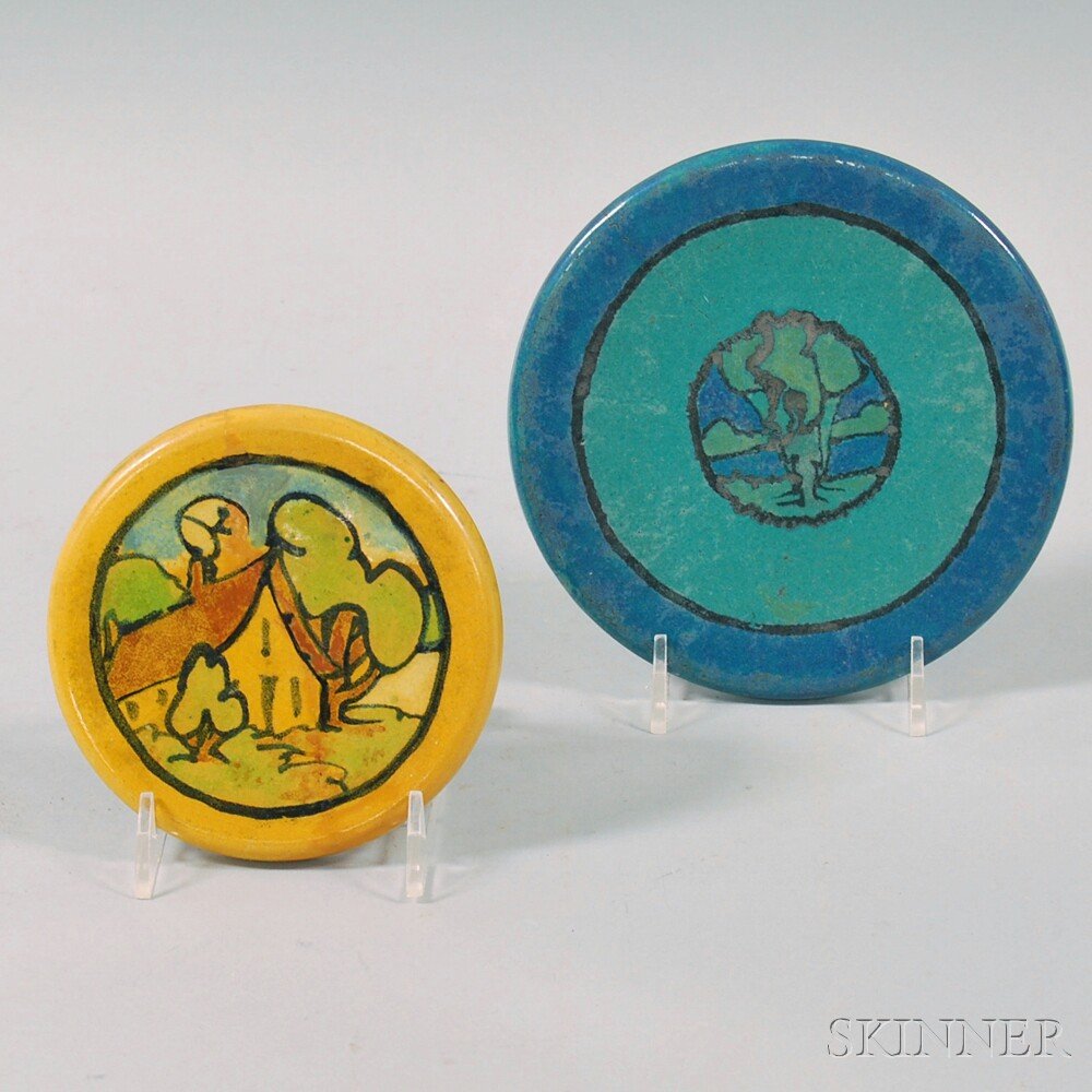 Two Saturday Evening Girls Tea Tiles, the larger in blu: Two Saturday Evening Girls Tea Tiles, the larger in blue glazes with central tree medallion, unmarked, the smaller in yellow glazes with cottage scene, and traces of Paul Revere Pottery stamp, dia. 5 