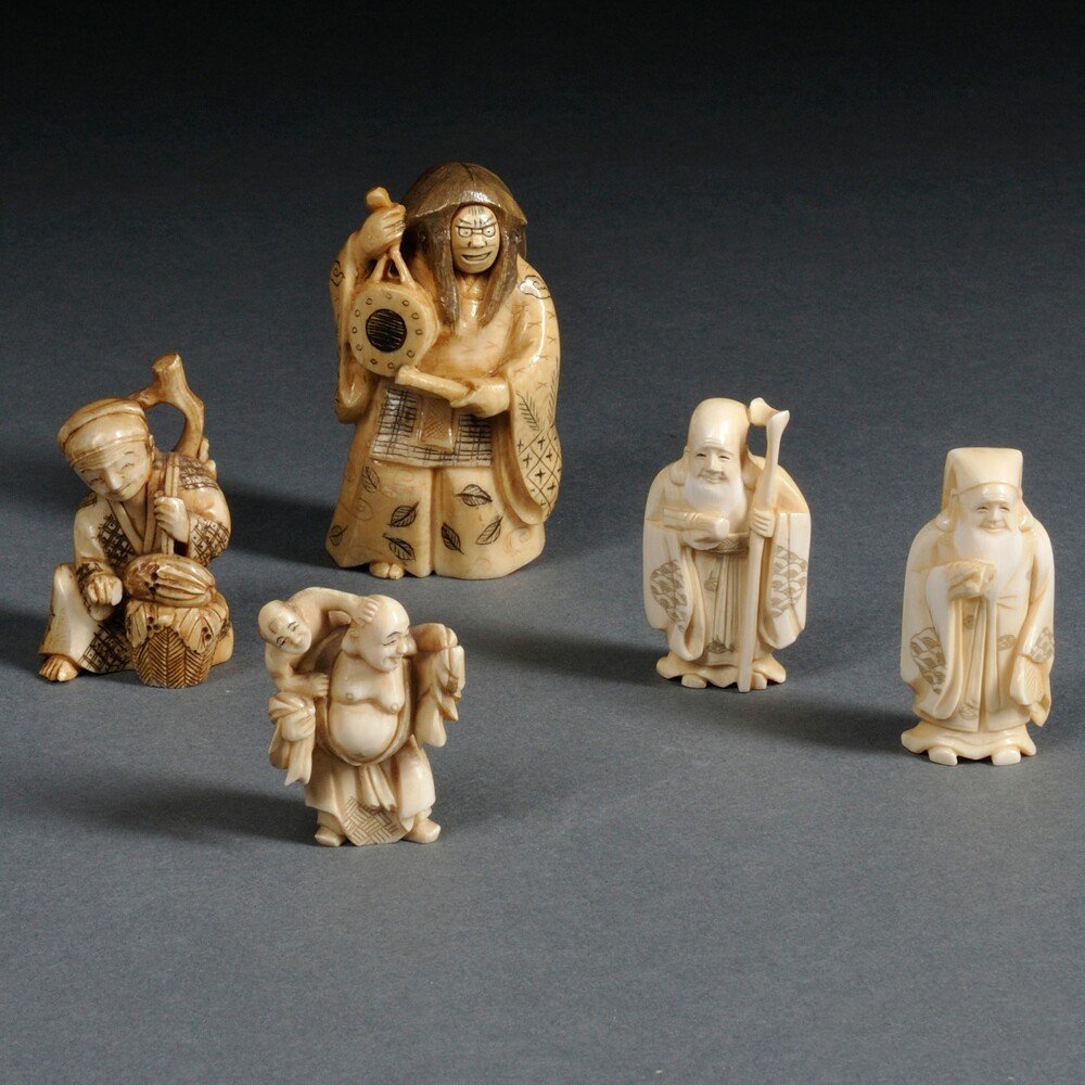 Five Carved Ivory Figurines, Japan, 19th/20th century,: Five Carved Ivory Figurines, Japan, 19th/20th century, a standing figure with two revolving faces, laminated, signed to base, ht. 2 7/8; two Immortals, one holding a toad and the other a scroll and a 