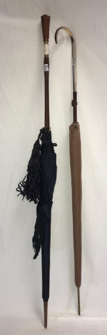 Vintage Saks Fifth Avenue Umbrella & Another: Italian black silk umbrella with fabric label for Saks Fifth Avenue sewn inside the protective sleeve. Wooden shaft with white bakelite carved decoration, and a black tassle. Together with a second um