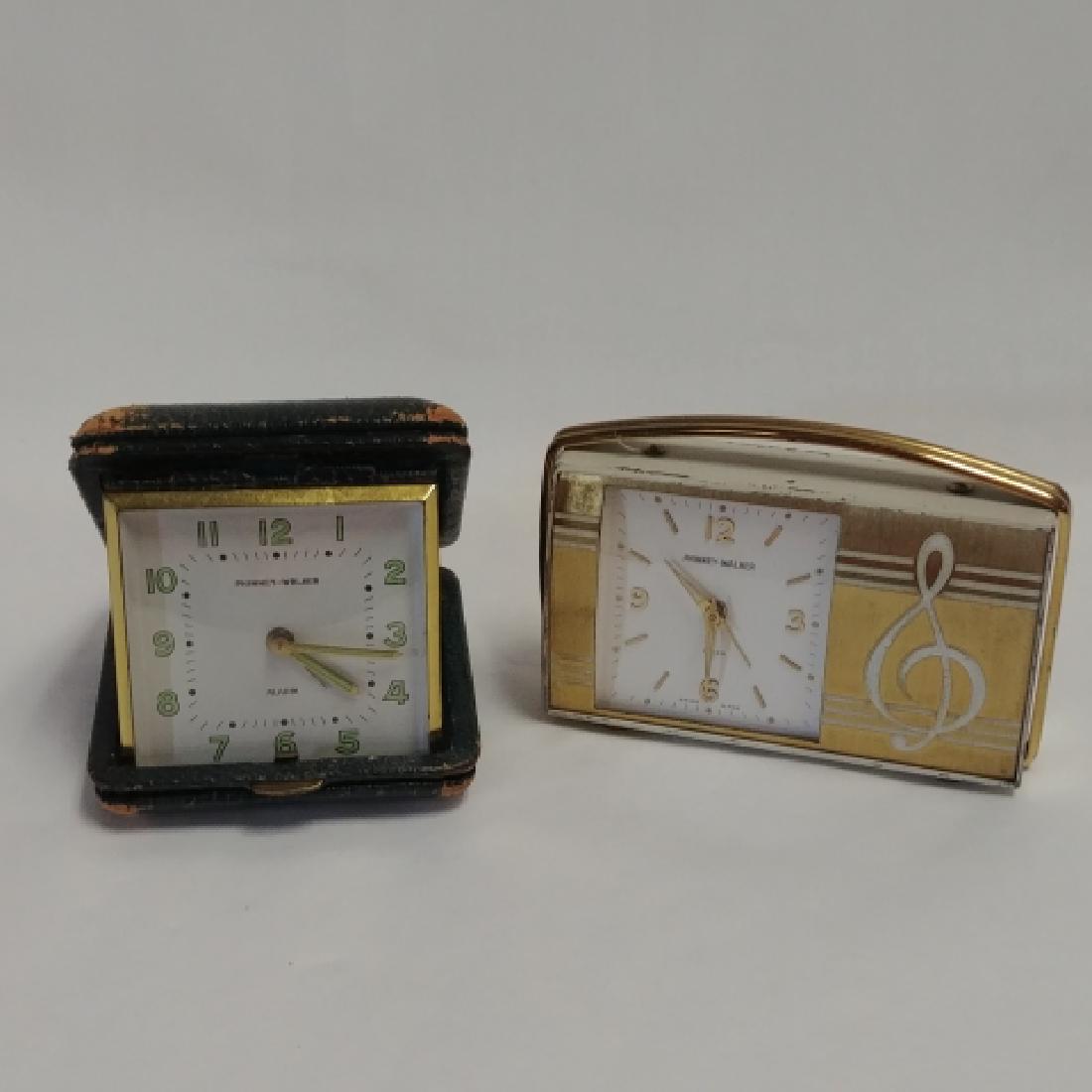 Two Phinney-Walker Travel Alarm Clocks: First is gilt and white painted. The second has glow in the dark numbers and hands in a worn leather case. 4-1/2" long; 2-1/2" wide