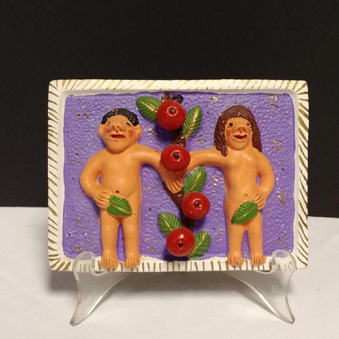 Folk Art Adam and Eve: Signed on the reverse Misterio, F.F. Painted and polychromed plaque with Adam and Eve separated by four large red apples on a purple background. 6-1/2" L x 5" H