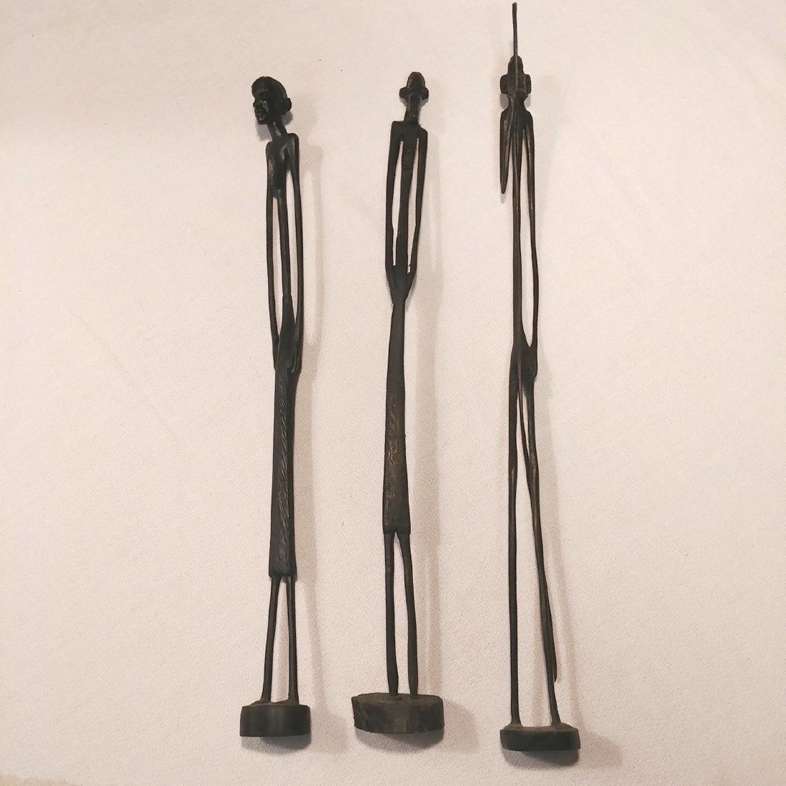 African Carved Figures (3): Two women and a man with spear. African "stick-figure" carved. One labeled at the base Hand Carved Made in Kenya. 12-1/2" H each