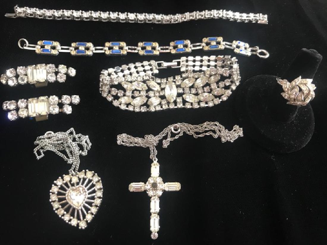 Rhinestone Jewelry Lot (7): Lot includes rhinestone tennis bracelet; rhinestone and blue stone bracelet; rhinestone cross on a chain; rhinestone ring; rhinestone bracelet; rhinestone shoe clips; rhinestone heart pendant on a cha