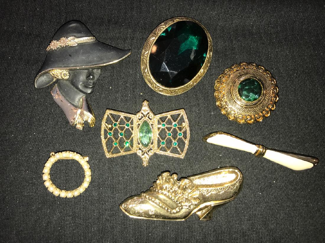 Lot of 1920's Style Gilt Pins (8): A woman in black hat marked Torino; high heeled ruffled shoe; oval green brooch; gilt and lattice brooch; circular scarf clip with green stone; faux pearl circle pin; and a Monet ribbon pin. 2-1/2" lo