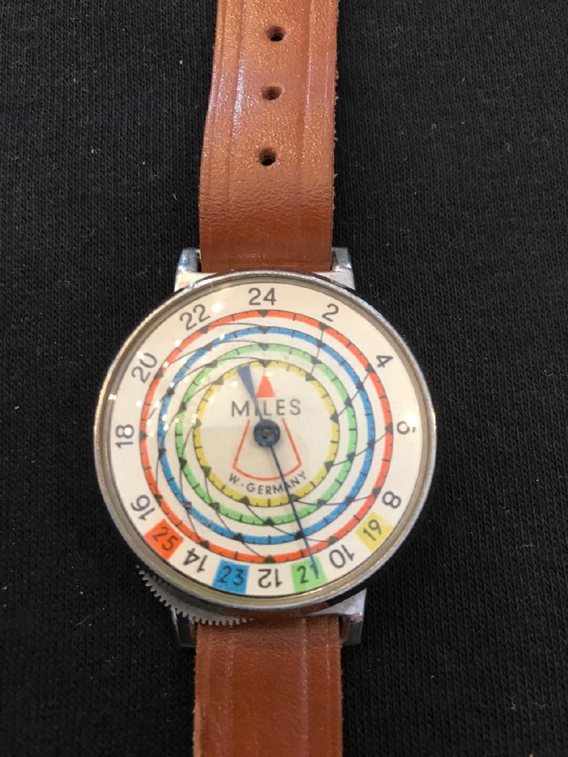 Miles Planimeter Military Device, W. Germany: Circa 1960's. US Military device worn like a watch and measures distance in miles. Colorful face reads MILES, W. Germany. Leather strap marked Made in Western Germany. 1-5/8" D