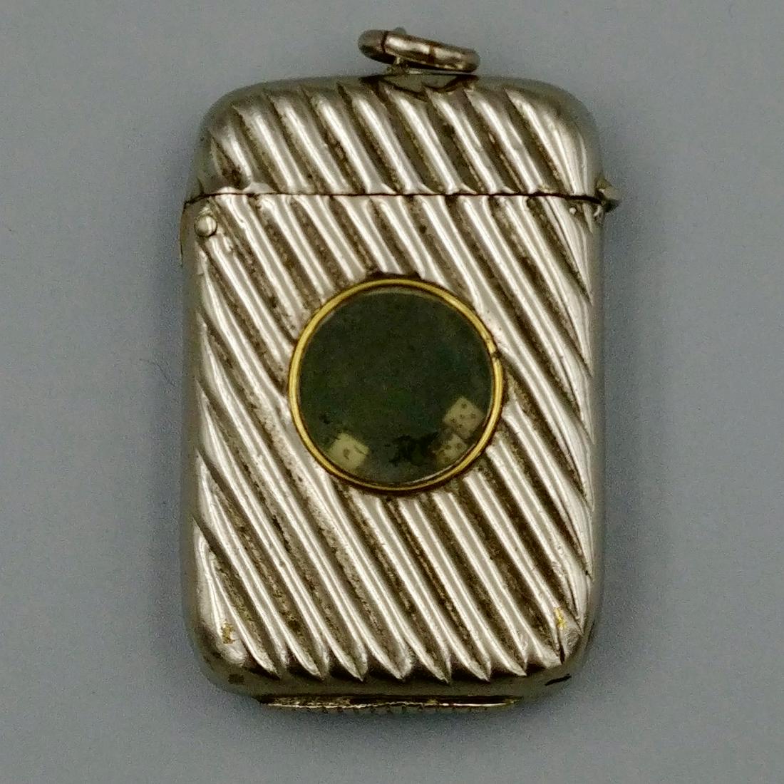 Novelty Dice Game Match Safe: Nickel plated. Three dice roll inside a glass covered impression on the case. Rib decorated. Striker on the base. Loop for a chain attached at the top of the lid.