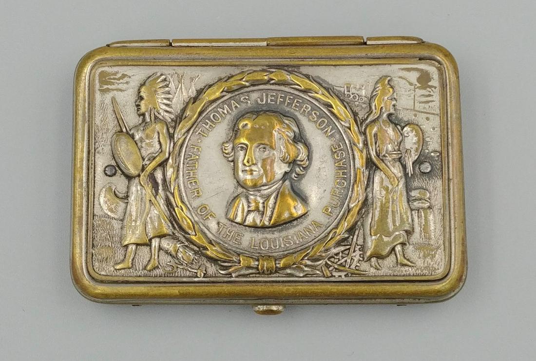 Nickel Plated Thomas Jefferson Match Safe: Two American Indians flank a circle with a raised bust of Thomas Jefferson, Father of The Louisiana Purchase. Press button to open the safe. Interior of lid has a framed window in which a sandpaper st