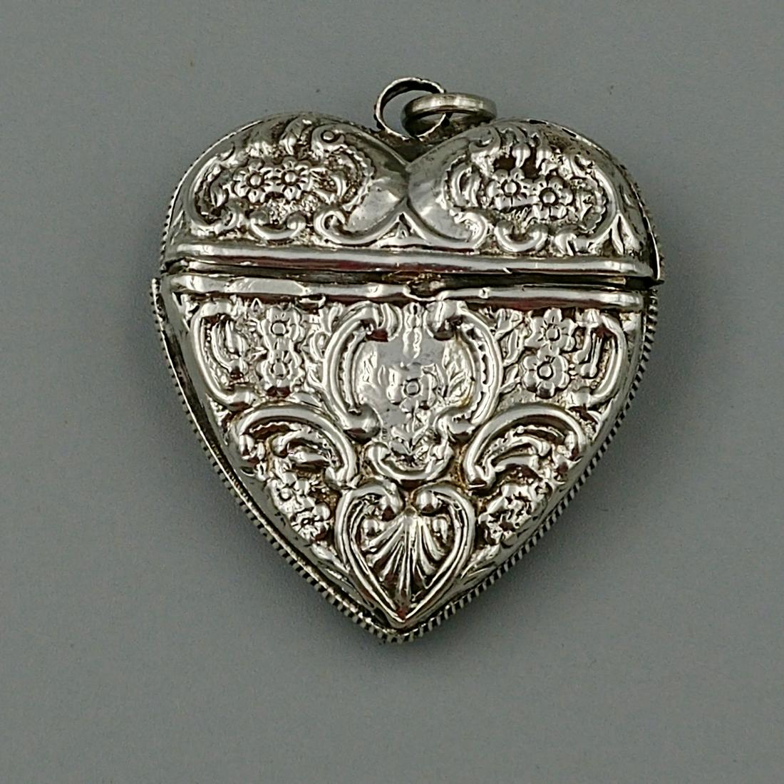 Sterling Silver Heart Shaped Match Safe: Marked 925 on the interior lip. Repousse all-over floral and scroll pattern. Loop at the top for a chain. Opens from the front toward the back. Striker all around the edge of the heart.