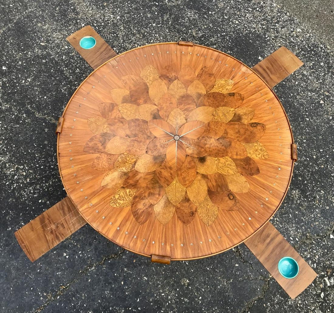 Round Inlaid Coffee Table: Coffee table with under table pull-outs - two teal glazed pottery saucers (maybe an ashtray) and two are flat wooden surfaces (maybe to hold a drink.) Glass top. 27" diameter x 18.5" High and the pull