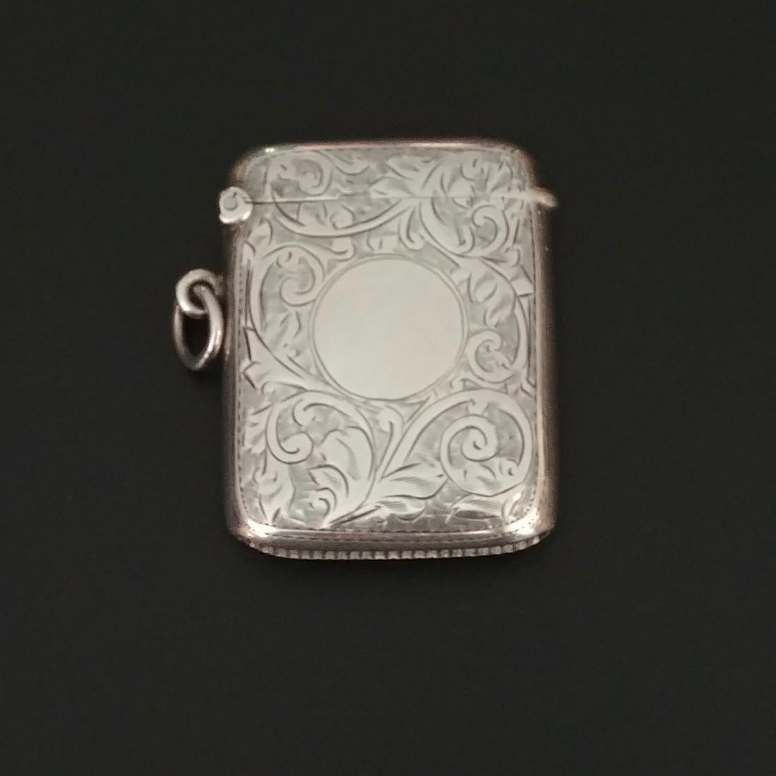 English Sterling Silver Match Safe: Hallmarked at the inside lip for 1921 Birmingham. By J. Gloster Ltd. Vine and leaf decorated. Area for monogramming. Flip top with deep striker at base. Loop and ring for attaching to a chain. Excelle