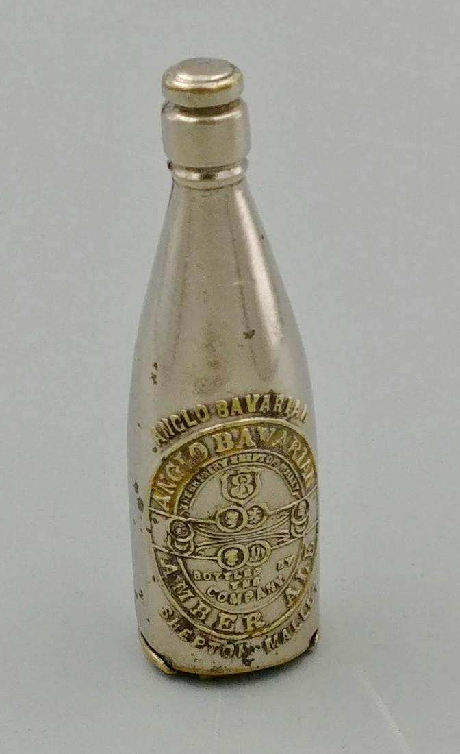 Liquor Related Match Safes (6): Nickel plated brass in the form of an ale bottle. The match safe is an advertisement for Anglo-Bavarian Amber Ale, Shepton Mallet. Base opens at the back. Striker on the lid of the base.Bottle is buil
