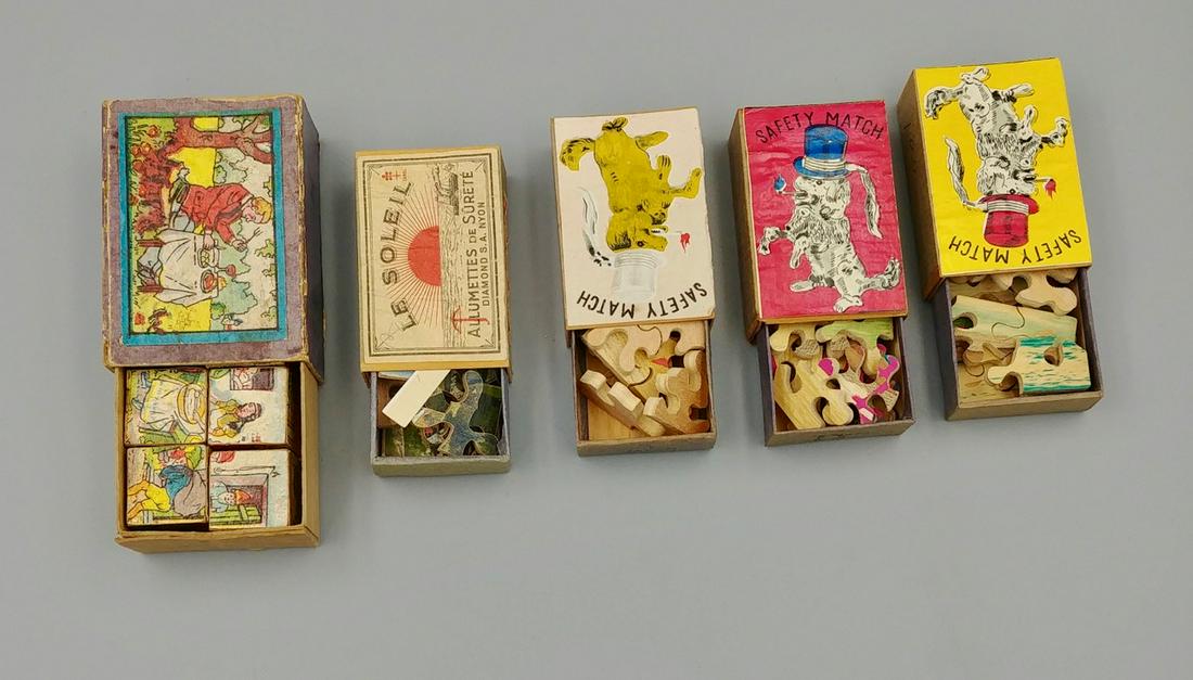 Lot of Match Box Puzzles (5): Box of 6 cubes that make up 6 different fairy tale scenes.; three wooden puzzles made in Japan marked Safety Match with a dog wearing a hat and holding a lit match in his mouth; the last a wooden puzz