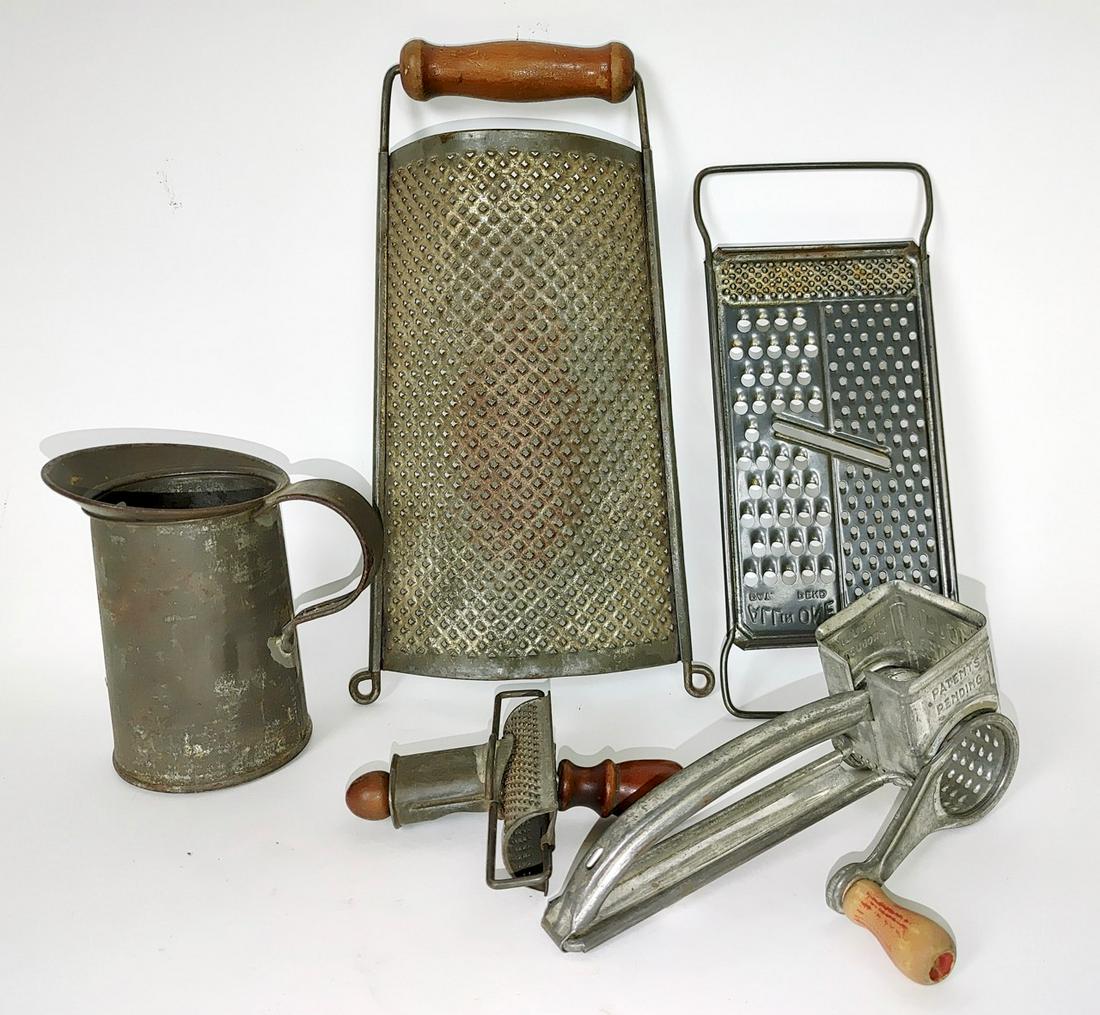 Lot of Vintage Kitchen Graters and a Tin Pitcher: Wooden handled grater; grater with several size; cheese grater; nutmeg grater; and a tin handled pitcher. 12" long the tallest