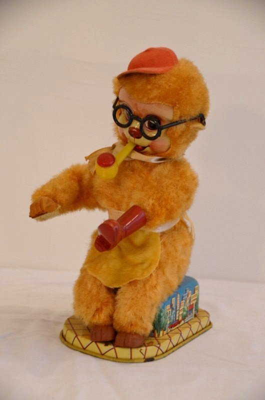 Shoeshine Toy Monkey: Smoking a pipe and shining a red boot. Tin base with city graphics. Battery operated. Made in Japan. 9" high