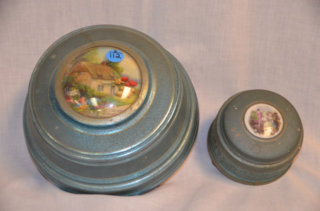 Two European Musical Metal Dresser Boxes: One has a glass three sectioned interior and plays Tales from The Vienna Woods. The other is a powder box. Unsure of the tune. 9" dia.; 4" dia.