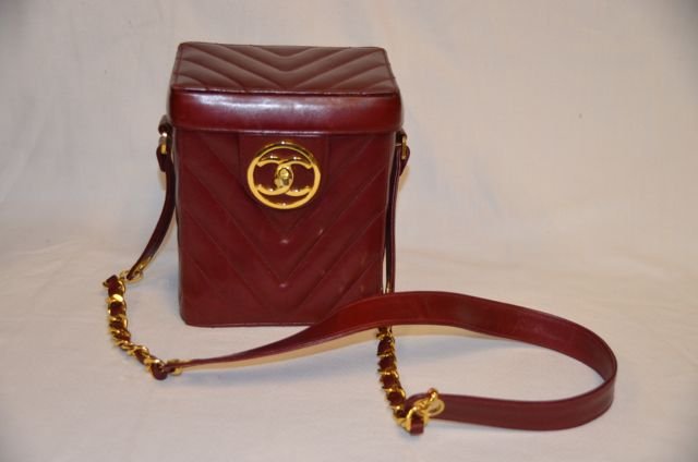 Vintage Chanel Leather Box Purse: Shoulder bag with gold tone chain. Red (wine color) chevron quilted leather with gold tone double "C" logo at clasp. Interior has a mirror and two zippered compartments. Marked Chanel in gilt stamp an