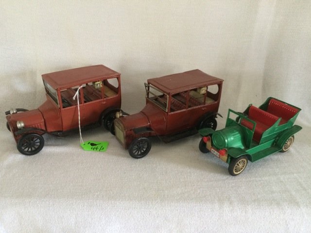 Pair Ford 1915 Tin Trucks and Another: A pair of Ford 1915 brown cars with nice interior lithography. Black fenders. One is missing a head lamp. Together with a green tin and plastic car with red interior and license plate AX-123. Made in 