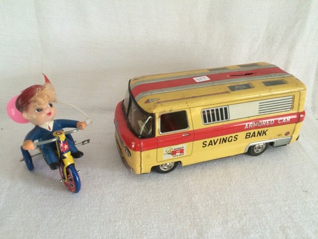 Tin Armored Car Savings Bank and Tricycle: Tin bank marked Rosko Tested (as is condition) together with a tin tricyclie with rider and bell. Made in Korea. MTU with a diamond logo. 10" long; 5" high